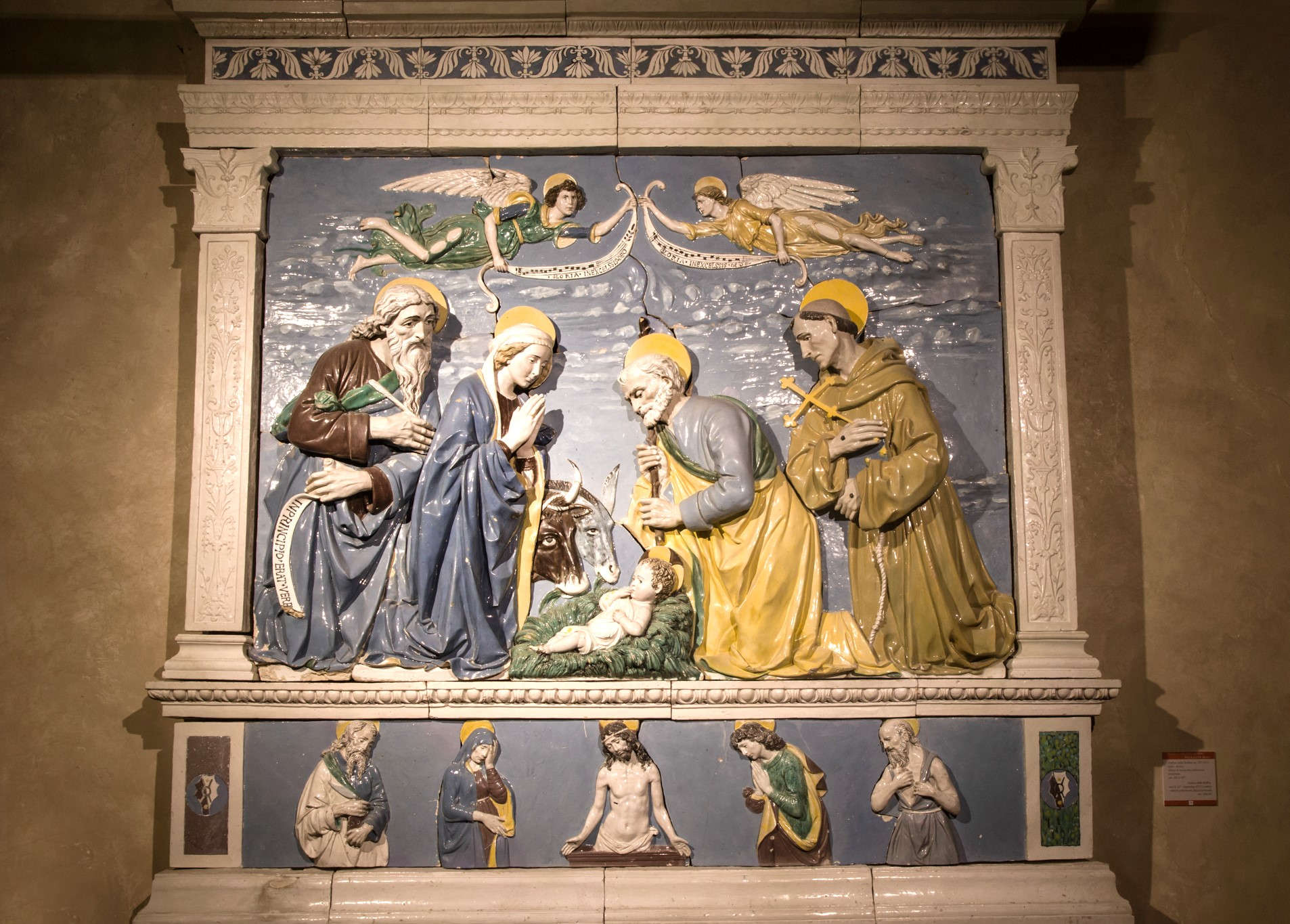 Andrea della Robbia, Geburt Christi zwischen den Heiligen Johannes dem Evangelisten und Franziskus (um 1490-1500; glasierte Terrakotta; Anghiari, Museo di Palazzo Taglieschi)